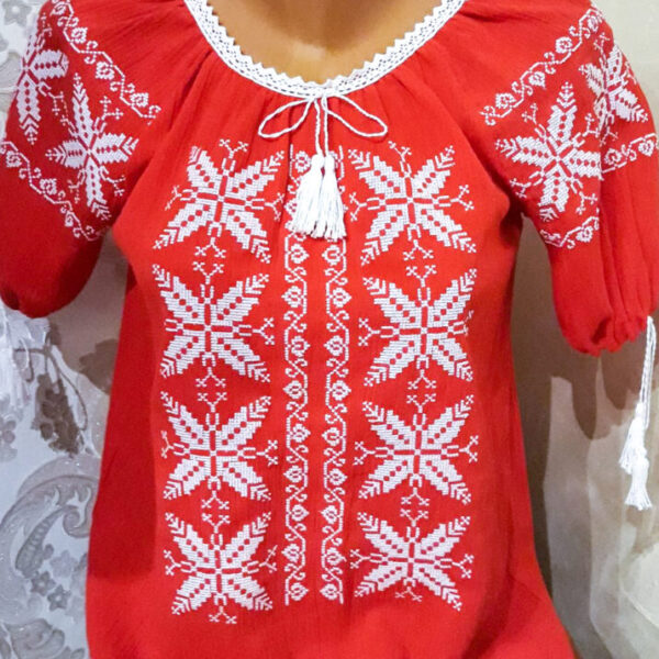 Ie traditionala de damă pe fond roșu  cu flori albe.